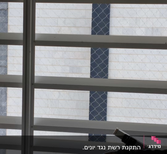 רשת מתכת על חלון למניעת כניסת יונים